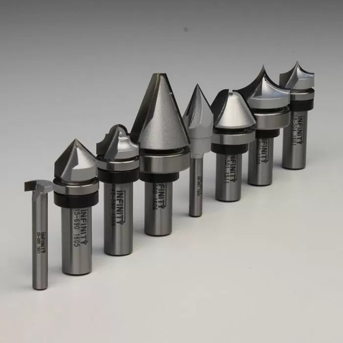 Assorted carbide-tipped router bits for woodworking, arranged in a row on a gray background.