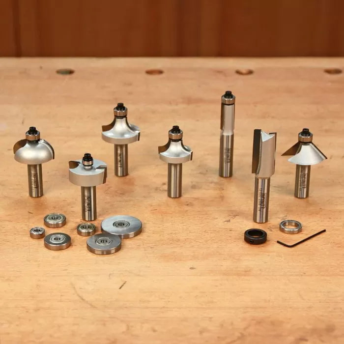 Assorted woodworking router bits and bearings set on a wooden workbench