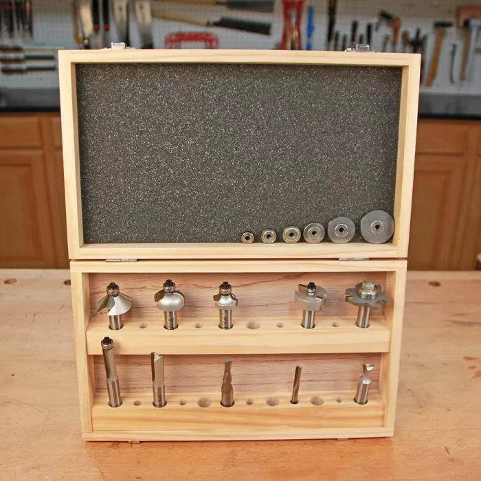 Wooden box with assorted router bits and bearings for woodworking on a workbench.