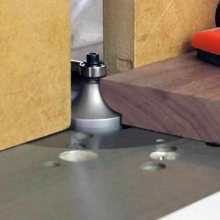 Woodworking router table with roundover router bit shaping the edge of a wood board