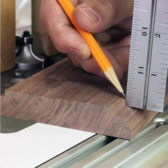 Woodworker marking a hardwood board with a pencil and metal ruler for precise cutting