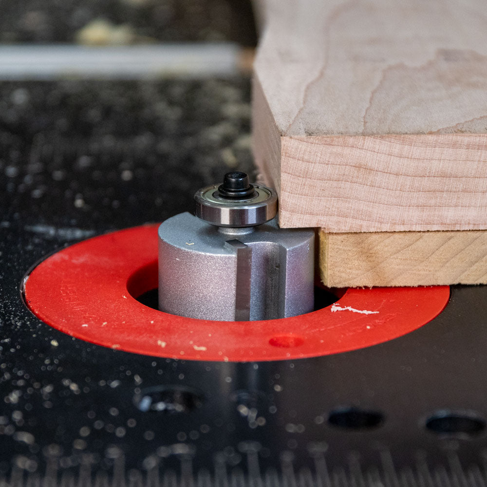 Woodworking router bit cutting edge on table with wood board, close-up