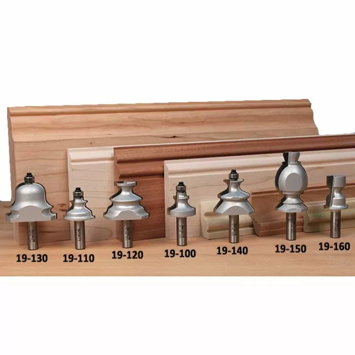 Assorted woodworking router bits with sample wood moldings and part numbers displayed