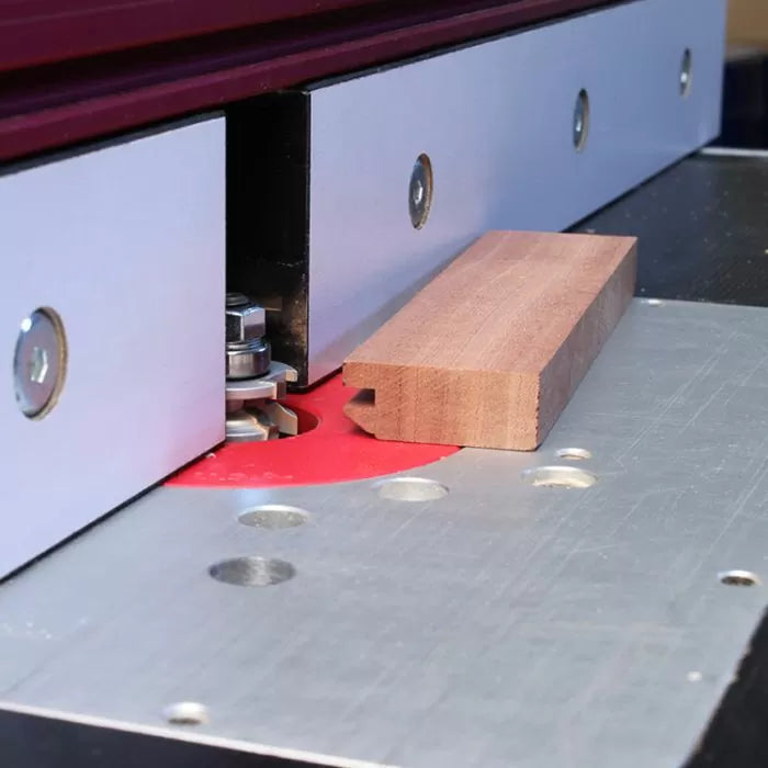 Wooden board on router table with fence and router bit for precise woodworking cuts