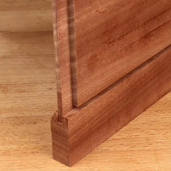 Close-up of a tongue and groove wood joint on a wooden workbench, ideal for woodworking projects.