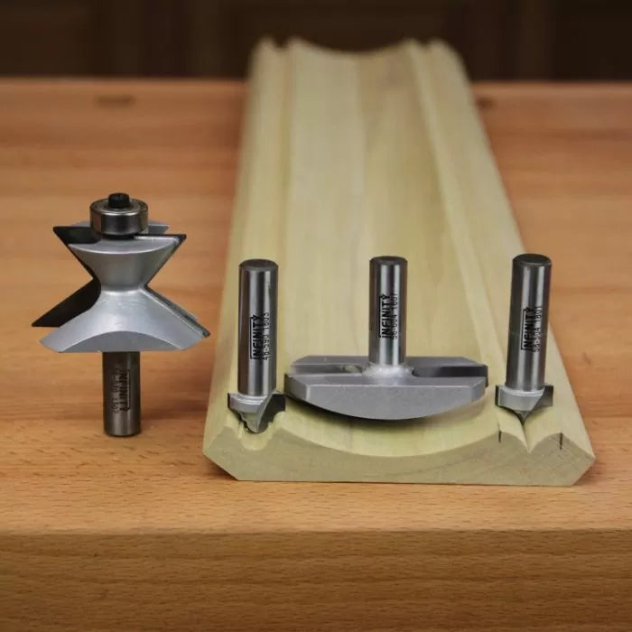 Woodworking router bits and molding sample on a wooden workbench
