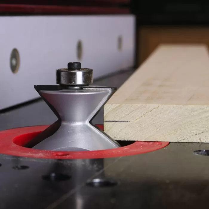 Router table setup with router bit cutting edge on wooden board for woodworking precision