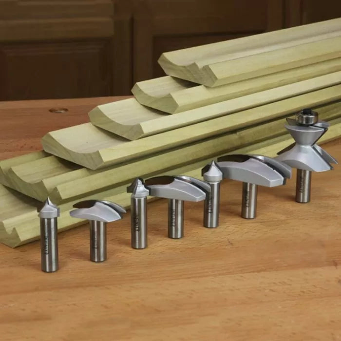Woodworking router bits set and shaped wood molding on a workshop table