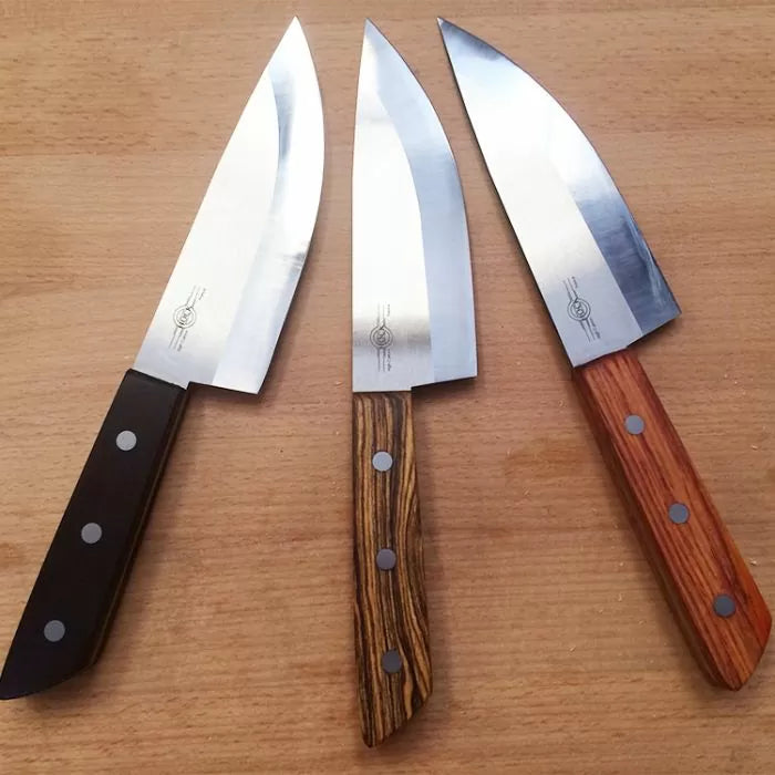 Set of three chef knives with different wood handles on a wooden surface, sharp steel blades