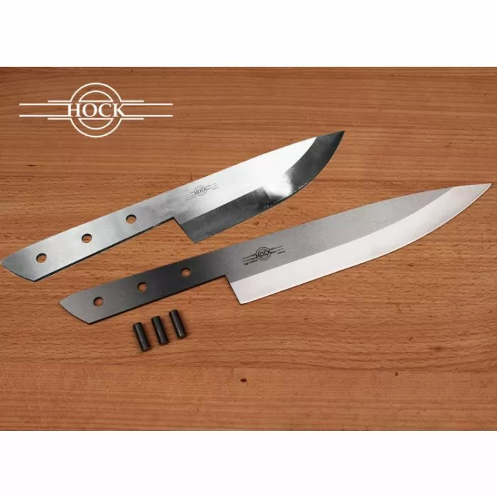 Two steel kitchen knife blades with drilled tangs on a wooden surface, handle pins included.