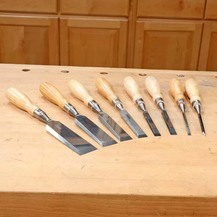 Woodworking chisels with wooden handles arranged on a workbench in a workshop setting