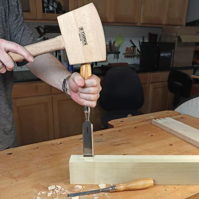 Woodworker using a mallet and chisel to carve a mortise in a wooden board