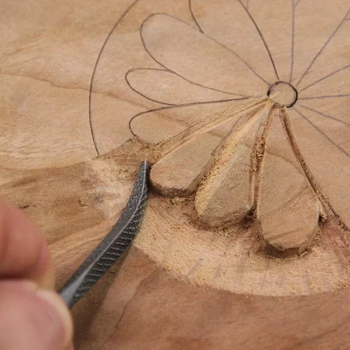Woodworker carving flower pattern into wood with hand chisel, close-up of woodworking detail.