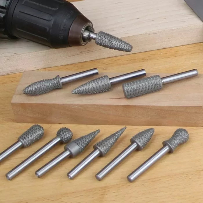 Carbide rotary burr set for woodworking, assorted shapes on wooden surface with drill