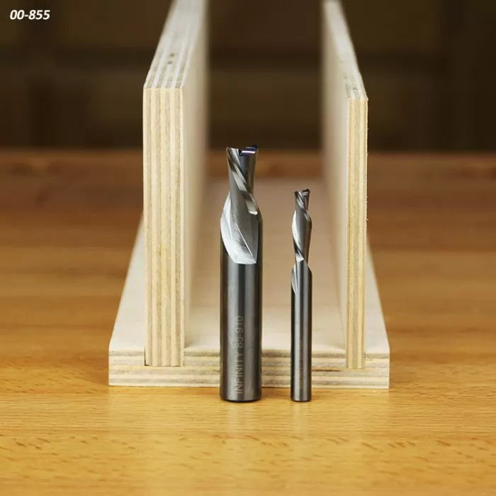 Two spiral upcut router bits with wood samples on a workbench for woodworking projects