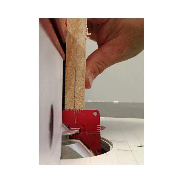 Measuring router bit height with red gauge tool and wood piece on router table