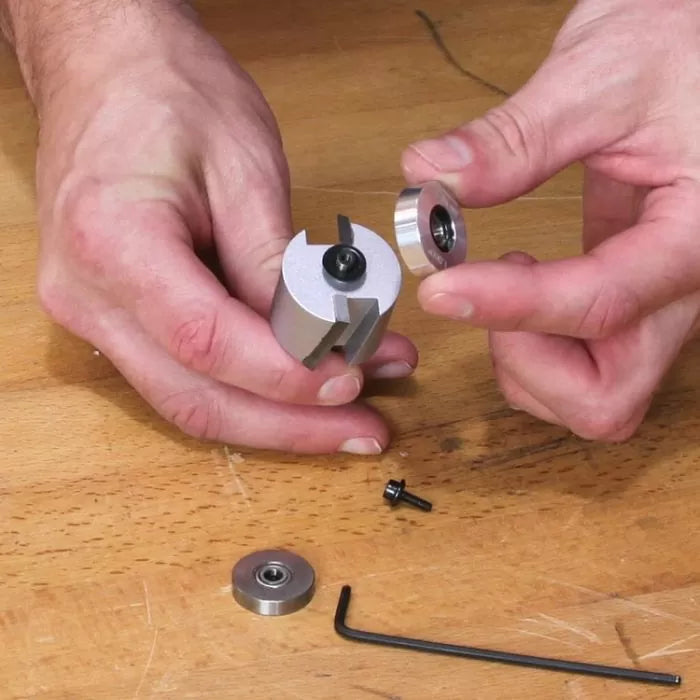 Person assembling a woodworking slot cutter router bit with bearings and hex key on workbench