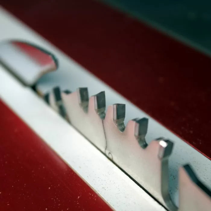 Close-up of a sharp table saw blade set in a red woodworking table
