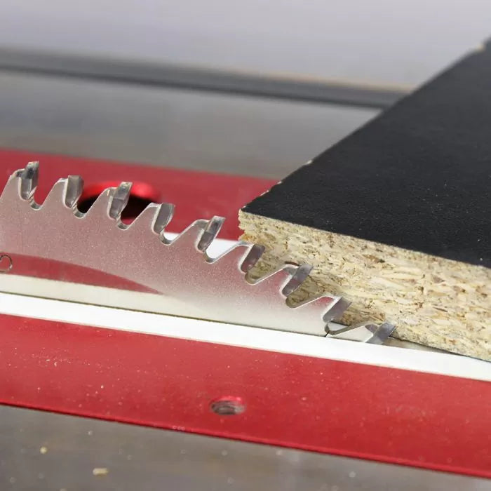 Close-up of a table saw blade cutting through laminated particle board