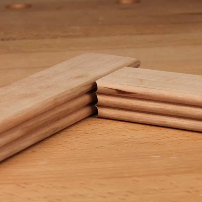 Close-up of mitered hardwood molding joint with decorative profile on wooden workbench