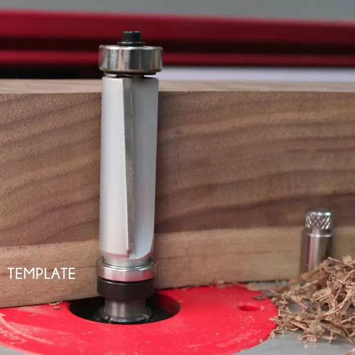 Template router bit with top and bottom bearings cutting wood on router table