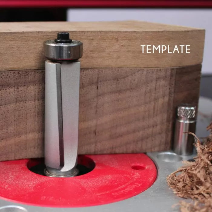 Template flush trim router bit cutting wood on a router table, woodworking setup shown.