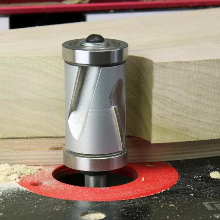 Carbide spiral flush trim router bit cutting wood on a router table
