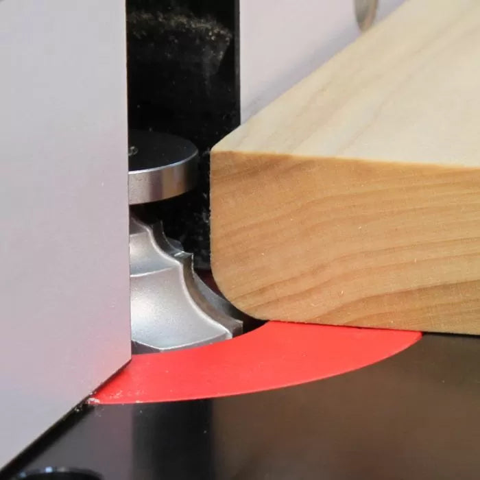 Close-up of woodworking router bit shaping edge of wooden board on router table