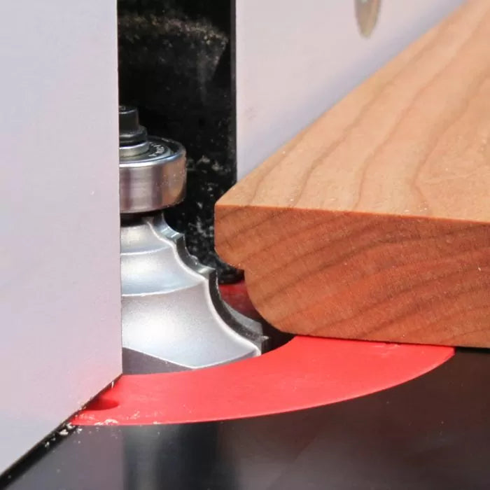Wooden board on router table with roundover router bit shaping the edge