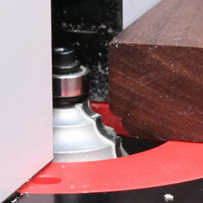 Close-up of a router bit shaping the edge of a wooden board on a router table