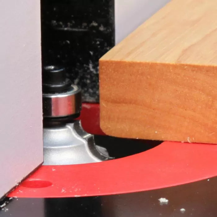 Close-up of a router table with a roundover bit shaping the edge of a wooden board