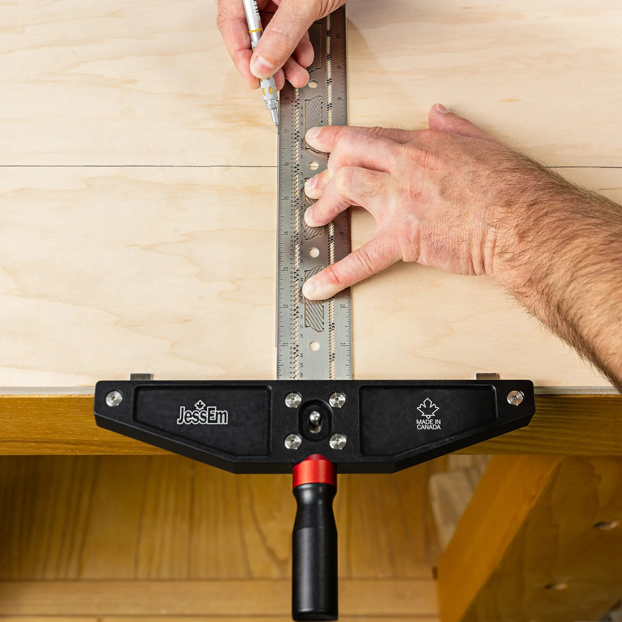 Woodworker using a metal marking gauge and ruler for precise layout on plywood.