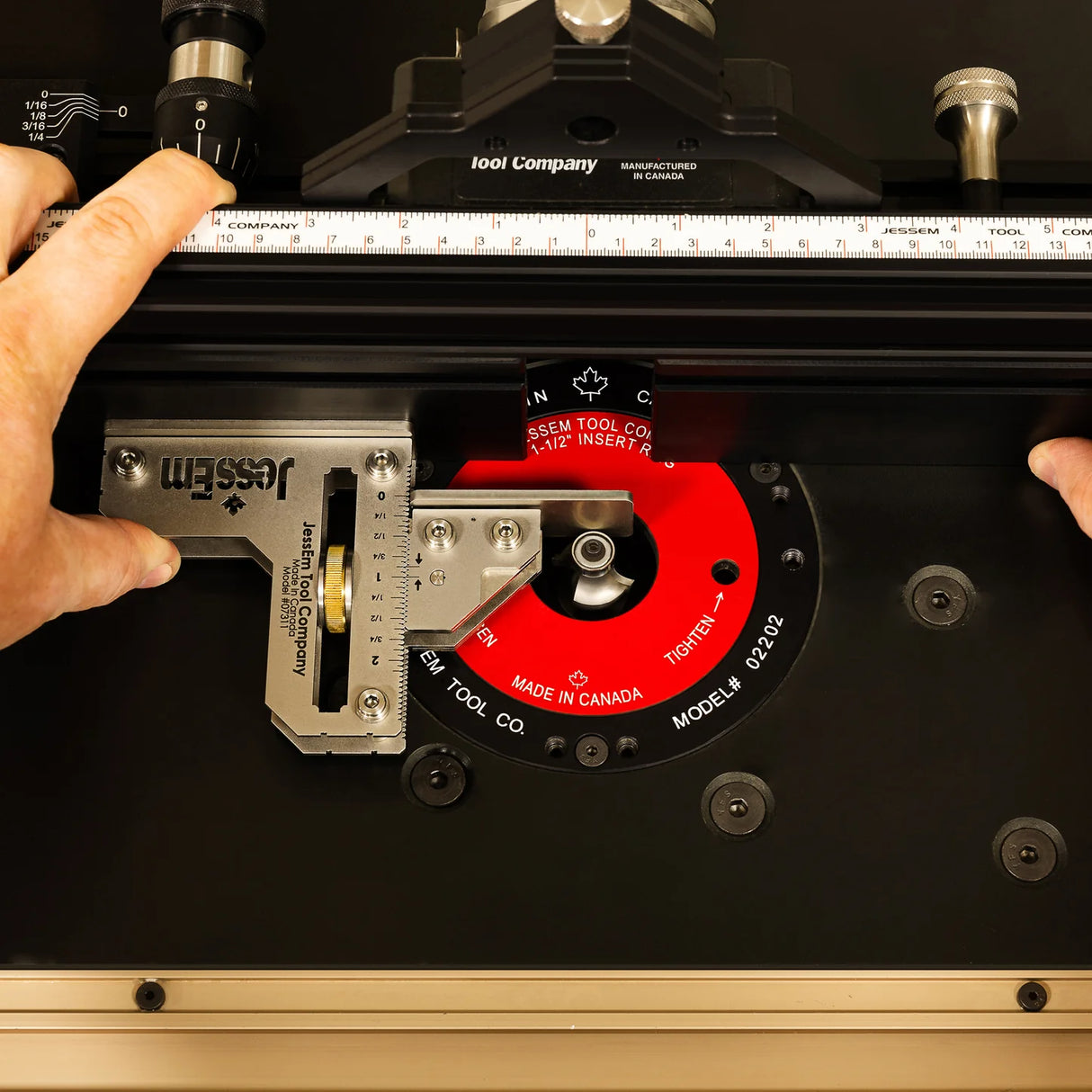 Close-up of hands adjusting a precision router table fence with measurement gauge and red insert ring.
