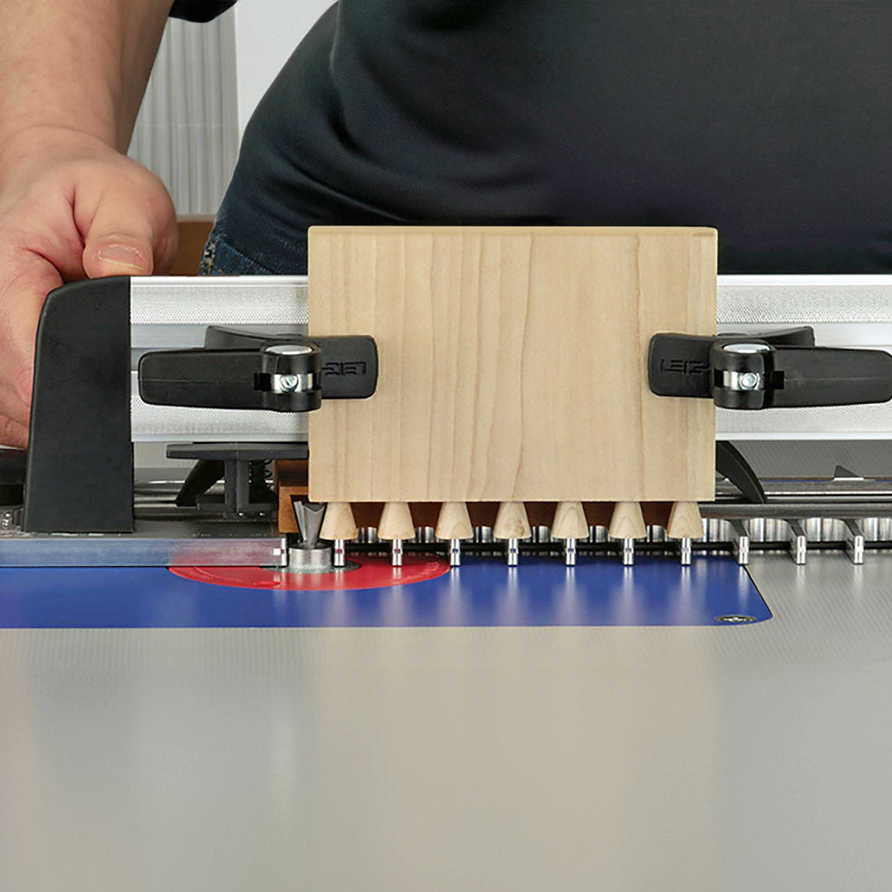 Woodworking router table with jig and router bit cutting dovetail joints in wood