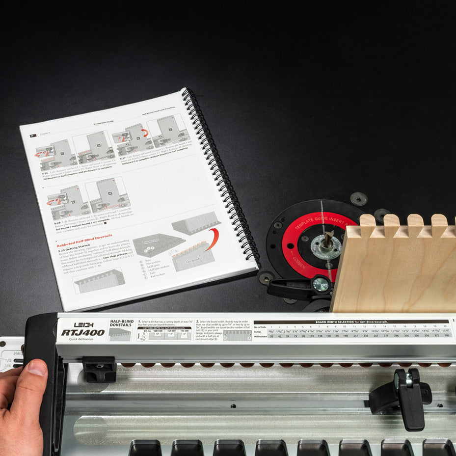 Dovetail jig setup with router table, spiral-bound manual, and wood joinery guide.