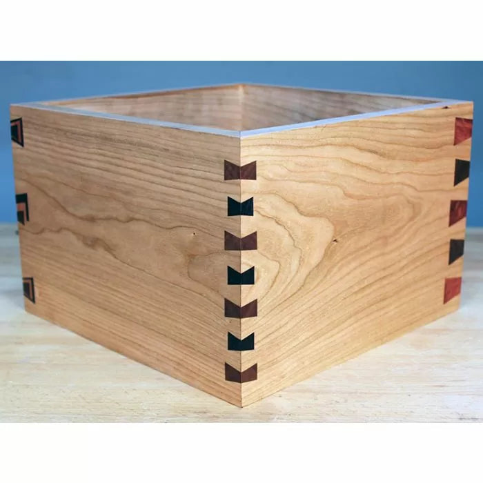 Wooden box with decorative dovetail and butterfly joints on a workbench, ideal for woodworking projects.