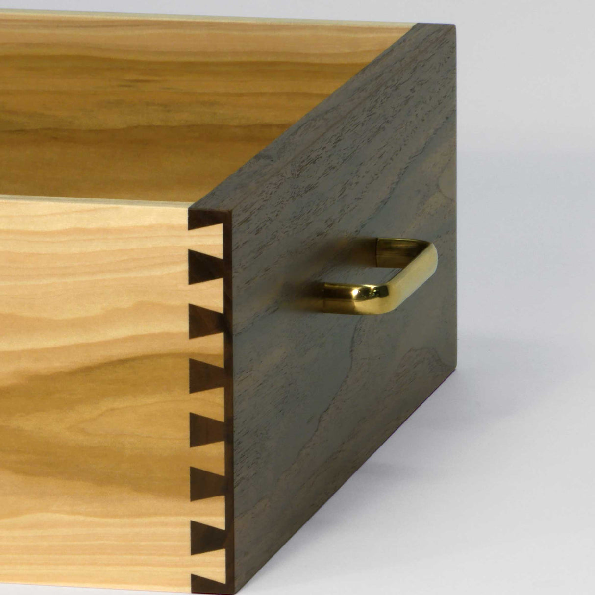 Close-up of wooden drawer with dovetail joints and brass handle, woodworking detail