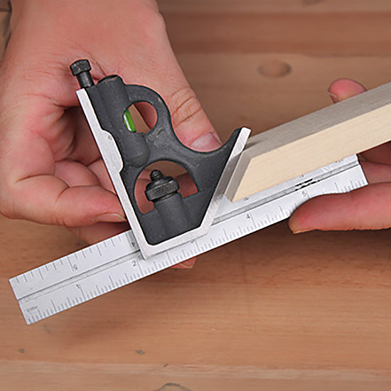 Hands using a combination square to measure and mark a piece of wood on a workbench