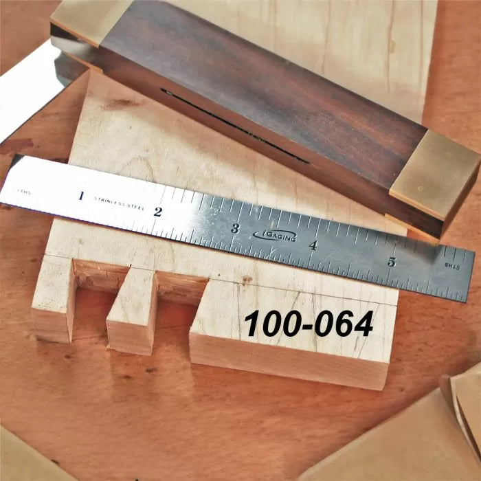 Woodworking dovetail joint sample with steel ruler and marking gauge on wooden surface