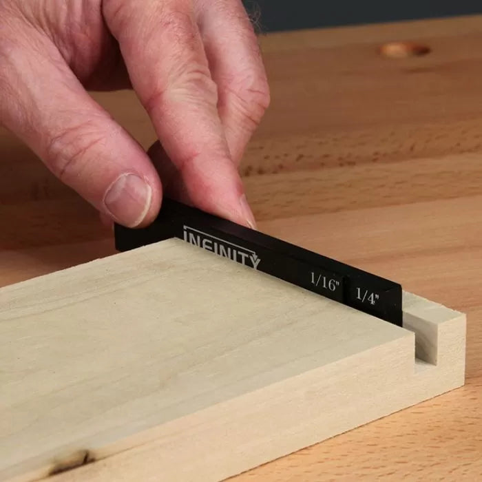 Hand using precision measuring gauge to check woodworking groove depth on wood board