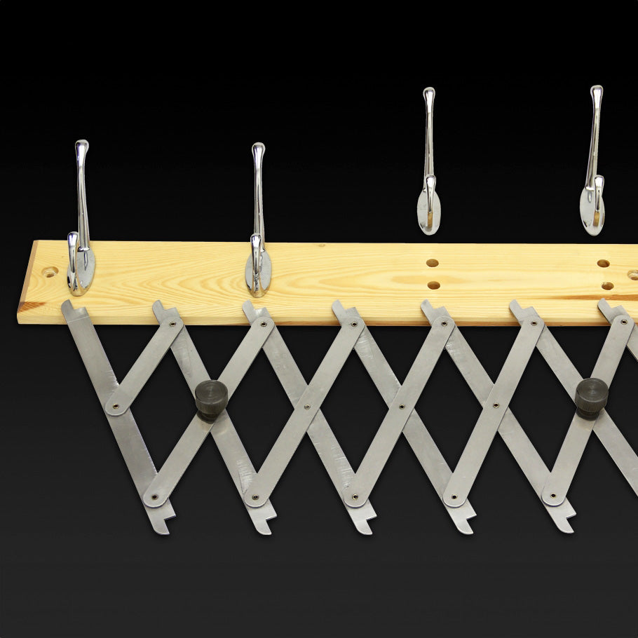 Stainless steel pantograph layout tool on a wood rack with metal hooks, black background.