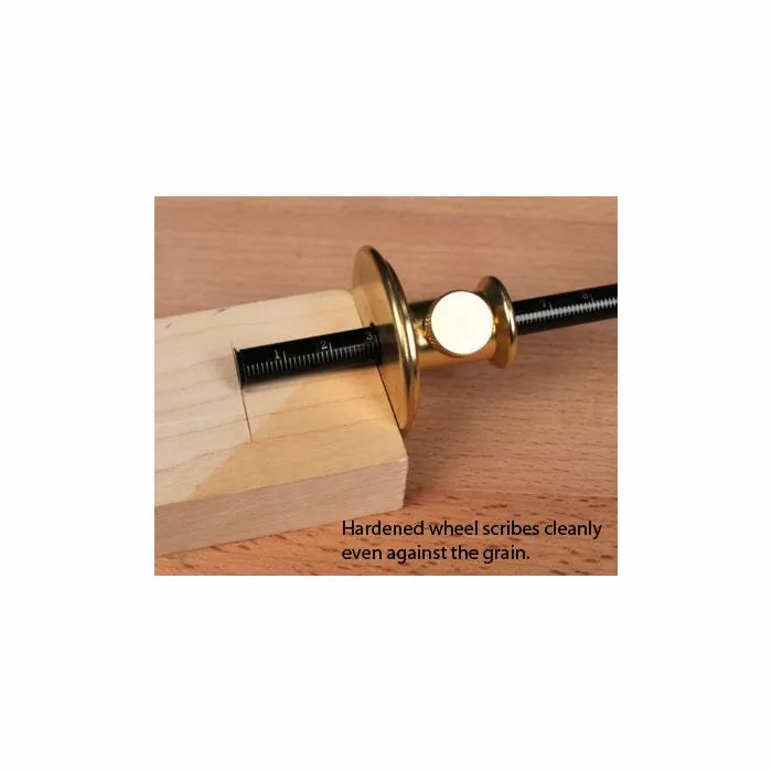 Brass woodworking marking gauge scoring a line on a wooden block with engraved ruler