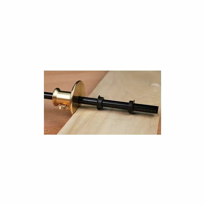 Brass and black marking gauge tool on light wood for precise woodworking layout