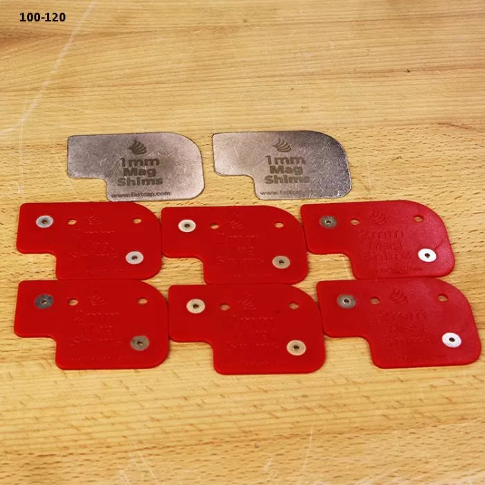 Set of red and silver 1mm magnetic shims on wood surface for woodworking tool setup