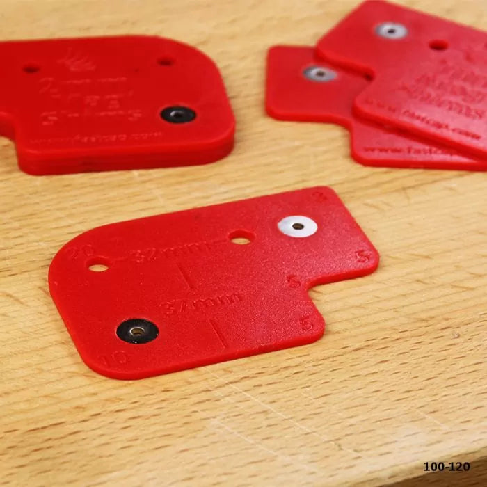 Red plastic woodworking jig templates on a wooden workbench for drilling precise holes.