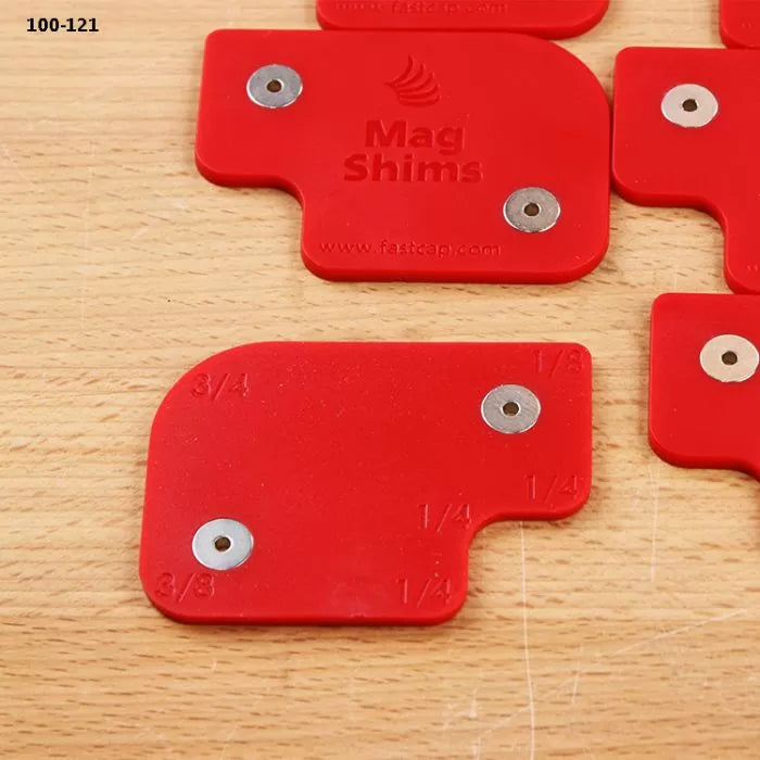Red magnetic shims for woodworking, labeled with measurements, on a wood surface.