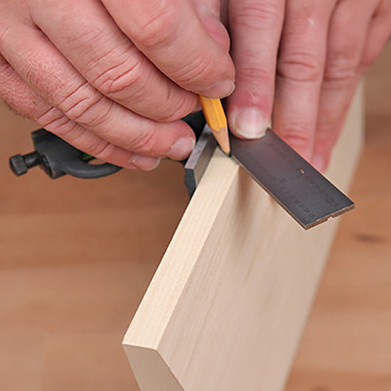 Woodworker marking a precise line on a board using a combination square and pencil