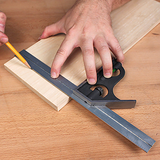 Woodworker using a combination square to mark straight lines on a wooden board