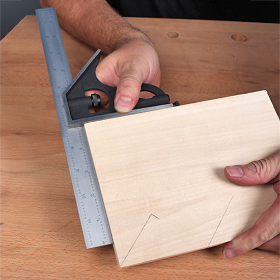 Woodworker using a combination square to mark lines on a rectangular wood board.