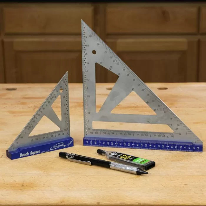 Metal woodworking bench squares, pencil, and lead refill on a wood workbench.
